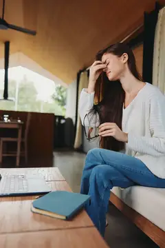 Уставшая темноволосая женщина с ноутбуком в кафе