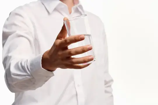 Бородатый мужчина пьет воду на светлом фоне