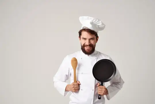 Весёлый шеф-повар мужского пола работает на кухне, занимаясь приготовлением пищи профессионально