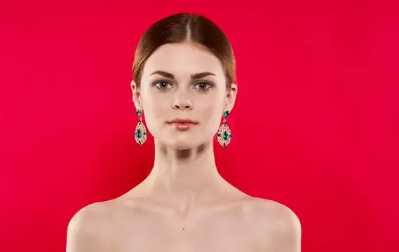 Молодая женщина с гладко зачесанными волосами и серьгами на красном фоне
