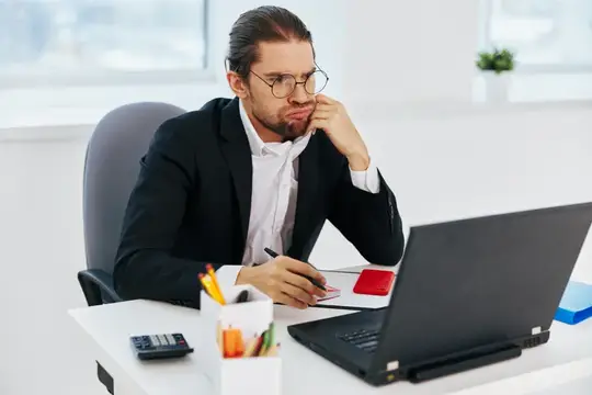 Задумчивый мужчина в очках за работой с ноутбуком в офисе
