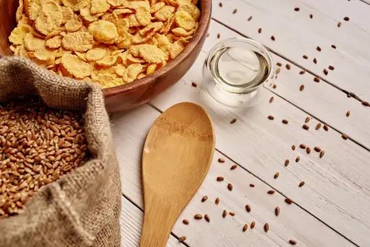 Миска кукурузных хлопьев, мешок зерна и деревянная ложка на столе