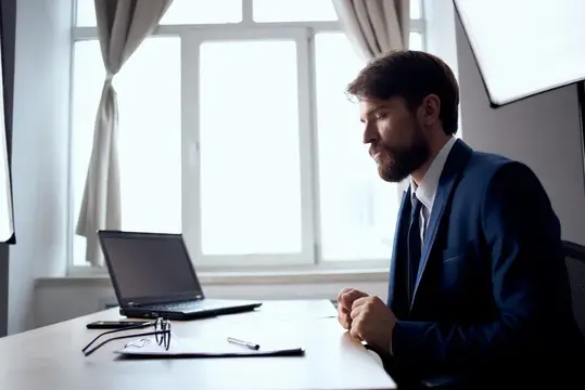 Менеджер работает за ноутбуком в офисе, испытывая эмоции, связанные с технологиями
