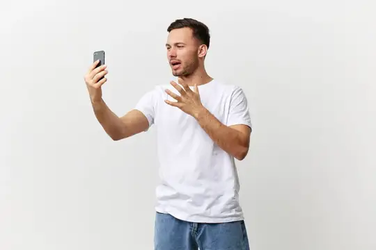 Удивлённый мужчина с телефоном в руке на белом фоне