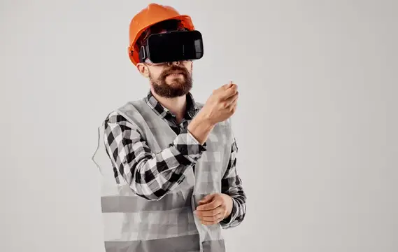 Строитель в оранжевой каске и VR-очках на сером фоне