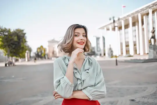 Жизнерадостная симпатичная женщина в красной юбке прогуливается на свежем воздухе