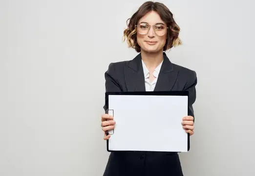 Женщина в деловом костюме с белым листом бумаги на работе, в очках, мокап