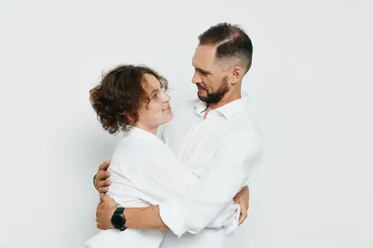Мужчина и женщина в белых рубашках нежно обнимаются на светлом фоне