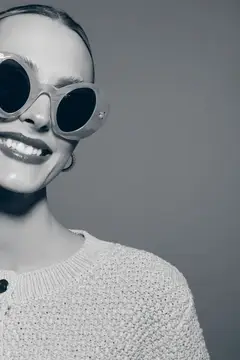 Улыбающаяся девушка в больших круглых солнцезащитных очках