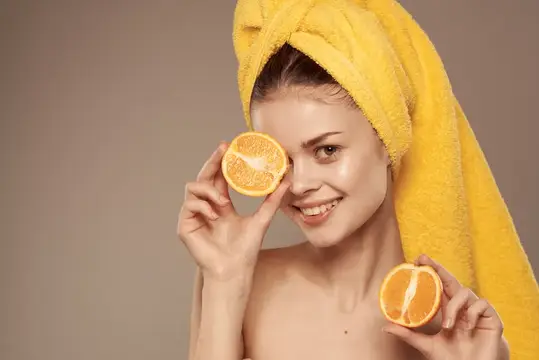 Жизнерадостная женщина с обнаженными плечами, апельсины, витамины, косметика, чистая кожа