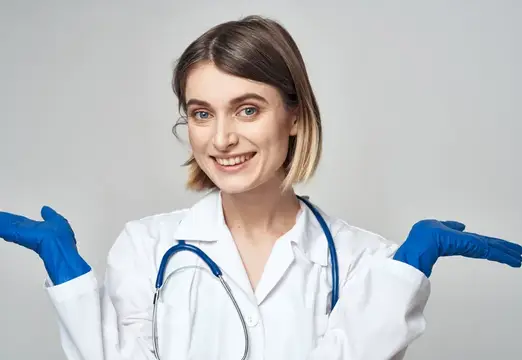 Медсестра в медицинском халате и синих перчатках жестикулирует, на шее у неё стетоскоп
