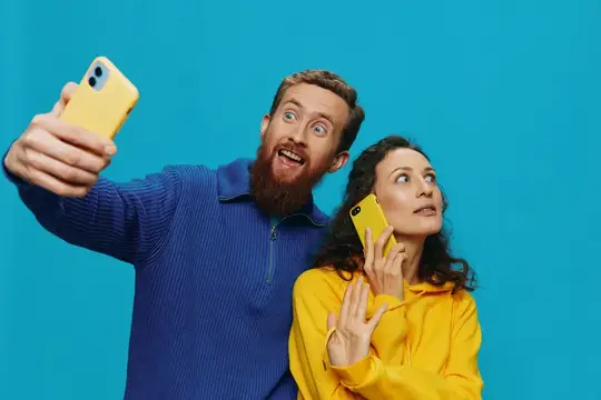 Бородатый мужчина и женщина делают селфи на жёлтые смартфоны