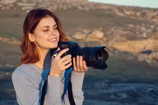 Жизнерадостная женщина-фотограф работает на открытом воздухе, среди природы, сочетая работу и образ жизни