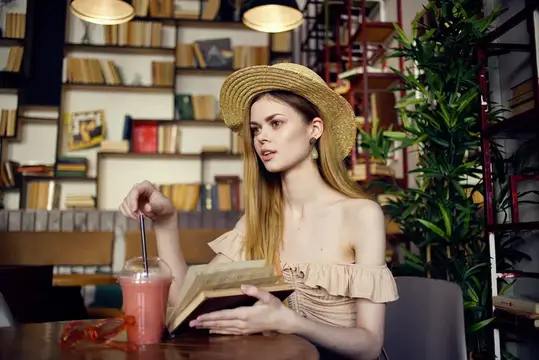 Женщина читает книгу, отдыхая в кафе, наслаждаясь напитком