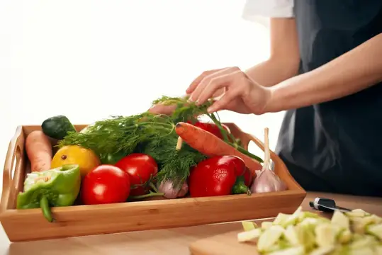 Женщина перебирает свежие овощи в деревянном ящике на кухне