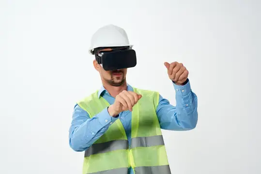 Мужчина в каске и VR-очках управляет жестами в светлой студии