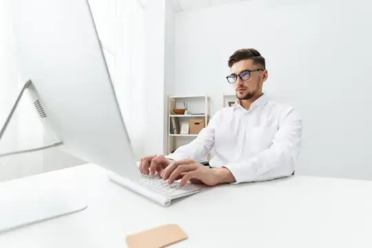 Красивый бизнесмен работает за компьютером в интернете, демонстрируя официальную уверенность в себе
