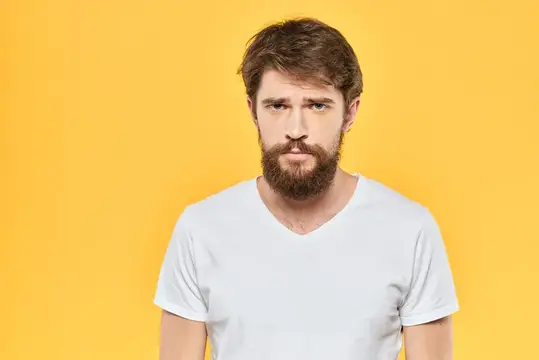 Бородатый мужчина в белой футболке на жёлтом фоне