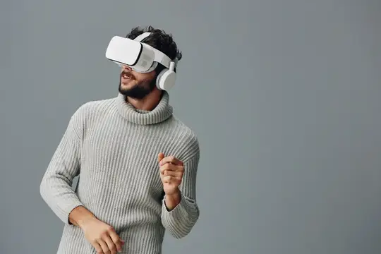 Улыбающийся бородатый мужчина в VR-очках и свитере