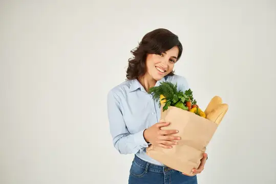 Симпатичная женщина с пакетом продуктов из супермаркета, крупный план