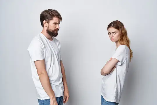 Мужчина и женщина в белых футболках отвернулись друг от друга после ссоры
