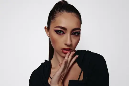 Портрет темноволосой девушки с ярким макияжем на светлом фоне