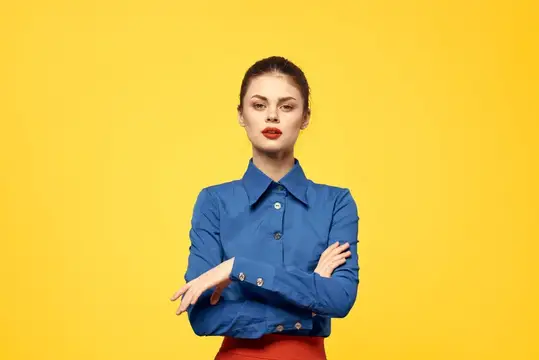 Уверенная девушка со скрещёнными руками на жёлтом фоне