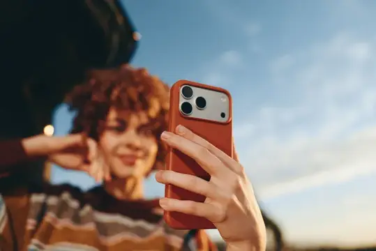 Рыжеволосая девушка делает селфи на смартфон в оранжевом чехле