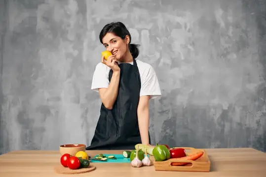 Улыбающаяся девушка в фартуке с лимоном на кухне