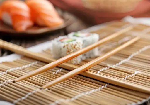 Деревянные палочки и роллы на бамбуковой циновке