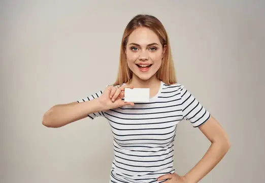 На фотографии высокого качества изображена симпатичная женщина в полосатой футболке, держащая в руке визитную карточку