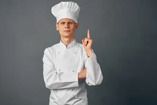 Шеф-повар мужского пола в профессиональной униформе работает в ресторане