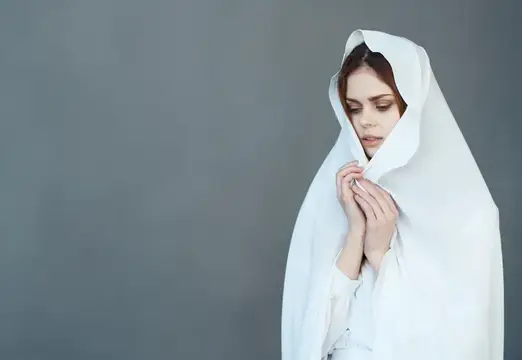 Молодая женщина в белом капюшоне на сером фоне