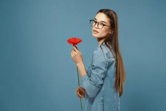 Брюнетка в очках с красным цветком, излучающая шарм и романтику