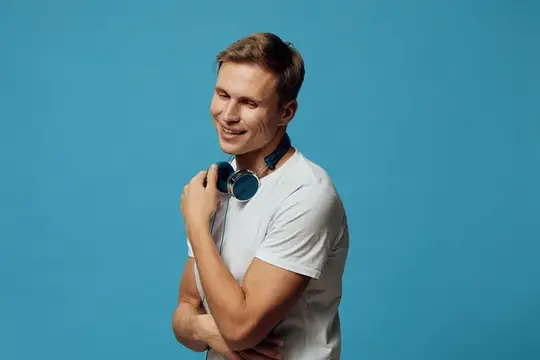 Улыбающийся парень в белой футболке с наушниками на синем фоне