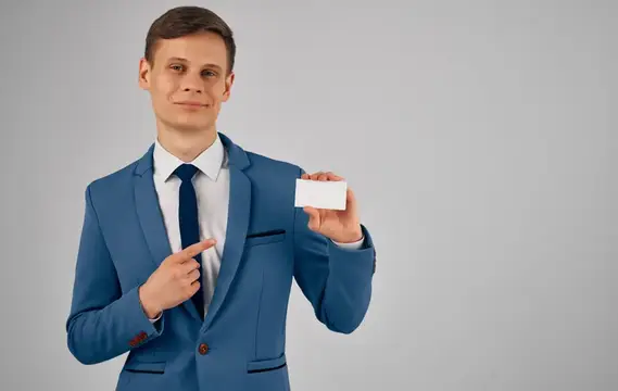 Молодой мужчина в синем костюме показывает на визитку