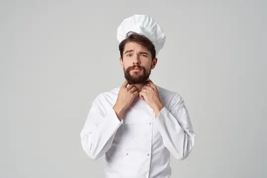 Бородатый мужчина в рабочей форме, профессия, кухонные принадлежности на светлом фоне