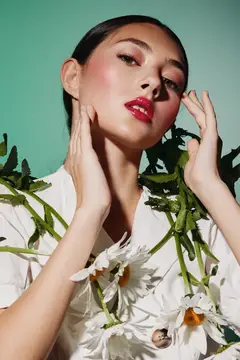 Портрет крупным планом женщины с сияющей кожей, ярко-красной помадой и свежими белыми цветами
