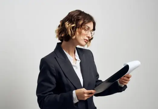 Деловая женщина в очках сосредоточенно изучает документы на светлом фоне