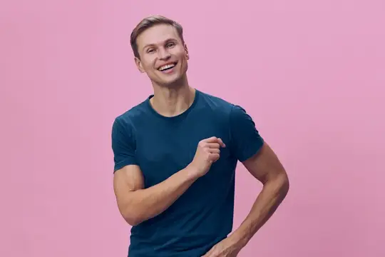 Улыбающийся светловолосый парень в синей футболке на розовом фоне