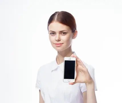 Молодая женщина в белой рубашке показывает смартфон на белом фоне