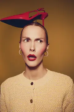 Удивлённая женщина с красной туфлей на голове