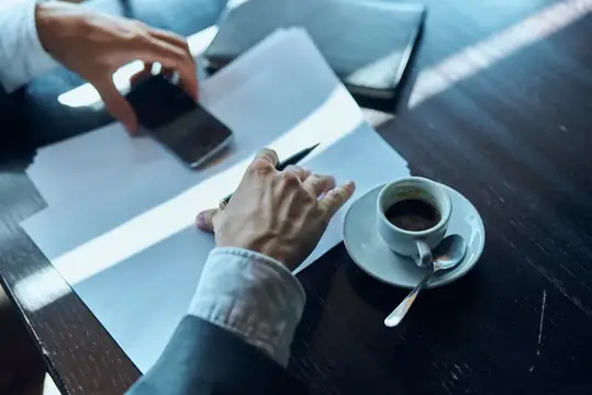 Бизнесмен в кафе с документами и чашкой кофе на столе, официальная работа