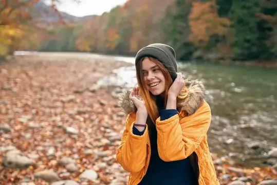 Веселая женщина в осеннем лесу у реки, свежий воздух