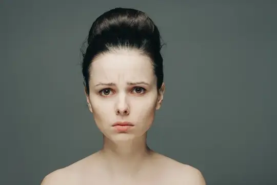 Молодая женщина с недовольным выражением лица на сером фоне