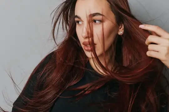 Молодая женщина с распущенными каштановыми волосами смотрит в сторону