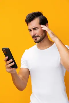 Задумчивый мужчина с телефоном на оранжевом фоне