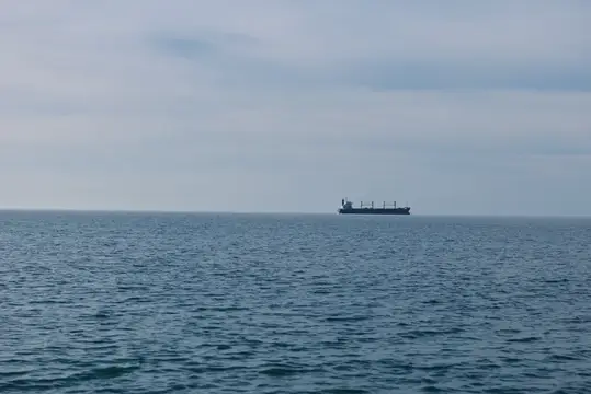Широкий океанский пейзаж с одиноким судном на горизонте, нежные волны и приглушенный свет, идеально подходит для тем логистики, судоходства, исследований или глобальной торговли