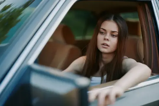 Задумчивая темноволосая девушка выглядывает из окна автомобиля