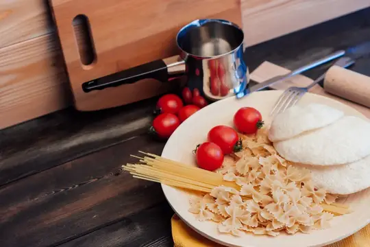Ингредиенты для пасты с помидорами и сыром на тёмном столе